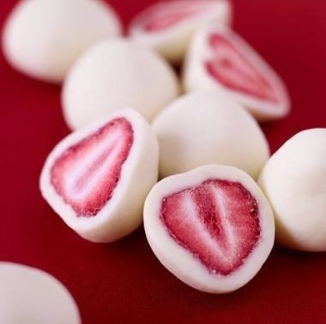 dolcetti per cani fatti con yogurt e fragole appoggiati su un tavolo rosso 
