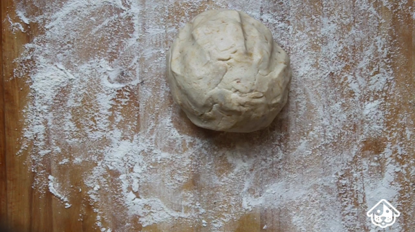 Hallowe'en dog treat dough in a ball on a floured surface ready to roll