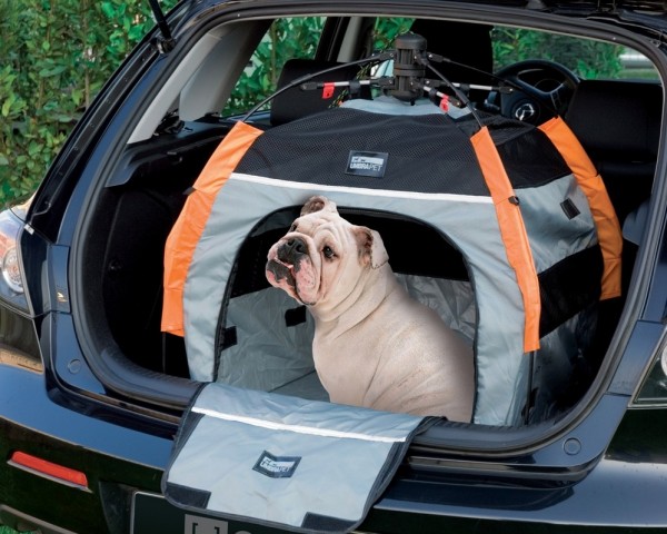 English Bulldog in a dog crate carrier in the boot of a volvo car travelling with dogs in a car