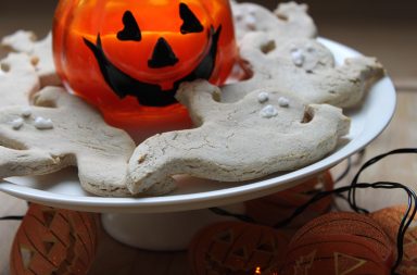 Halowe'en Dog Treat Recipe cookies with a pumpkin candle and fairy lights on a cake stand
