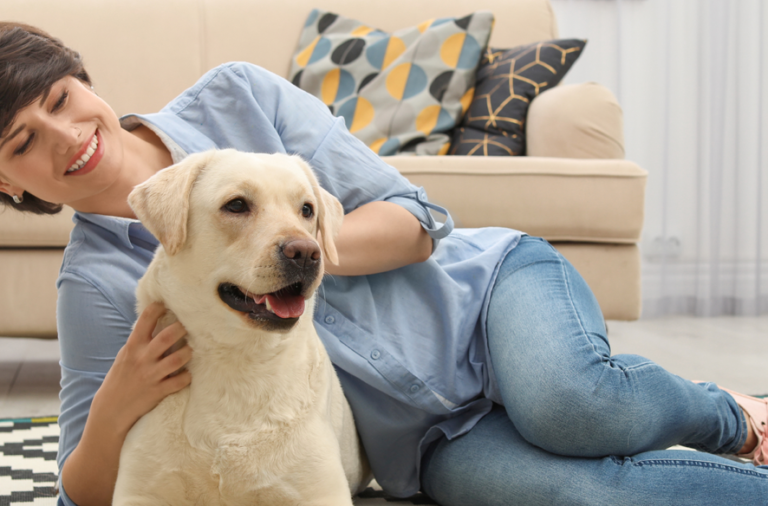 Image of a woman cuddling lying on a rug stroking her Labrador dog